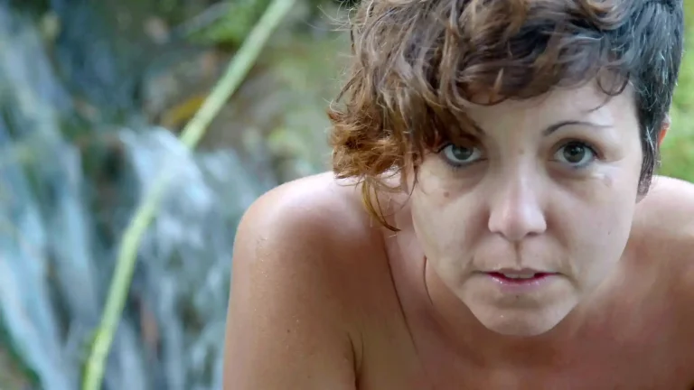 Jana de frente mirando a cámara. Tiene el pelo corto y un flequillo lateral izquierdo. Aparentemente, está desnuda.